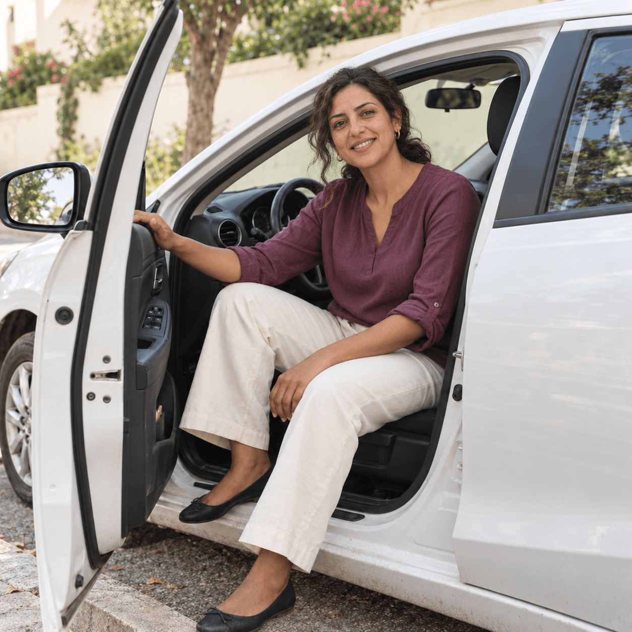 Une chauffeuse sourit, assise dans son véhicule à la portière ouverte