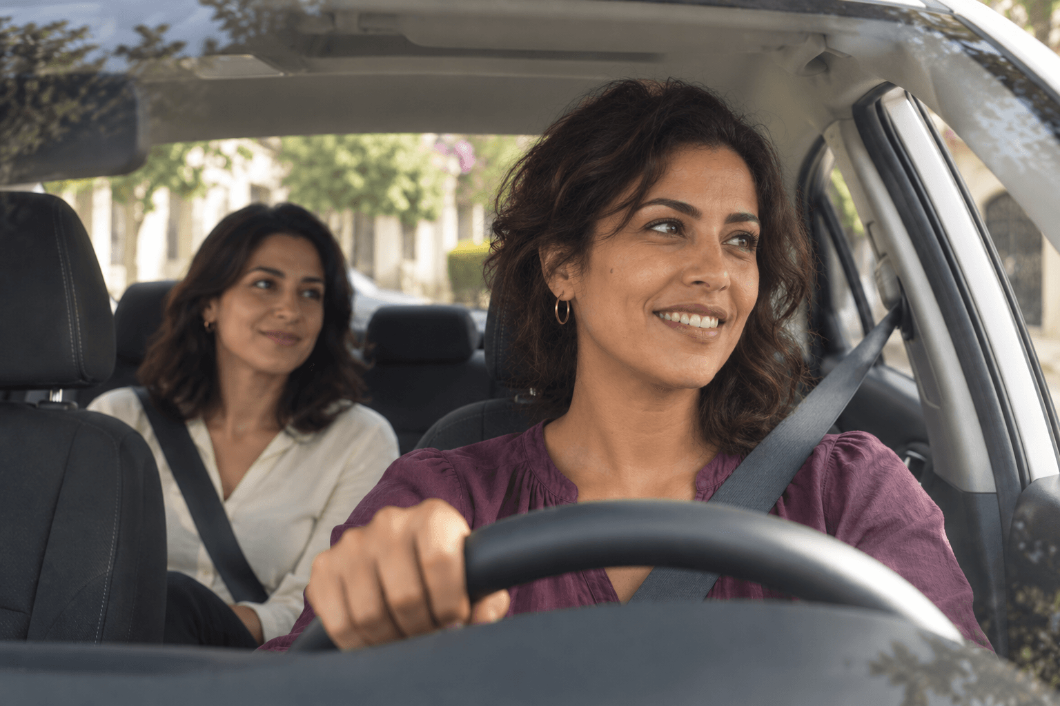 Une passagère et sa chauffeuse partagent un sourire dans une voiture lumineuse